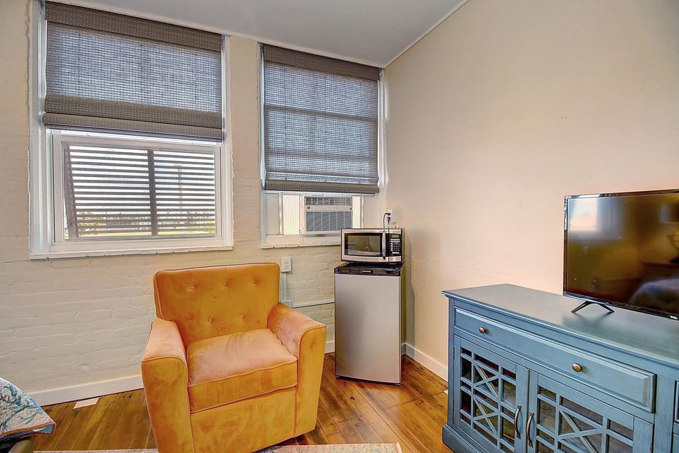 Settle into your cozy corner with a vibrant orange armchair, mini-fridge, and entertainment center—perfect for unwinding after exploring.