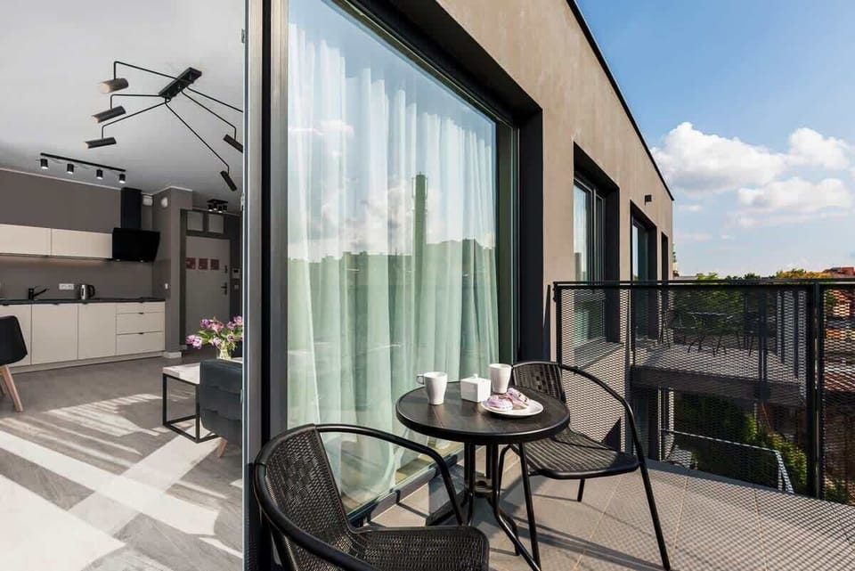 A small balcony furnished with a round table and chairs, providing a charming outdoor space.