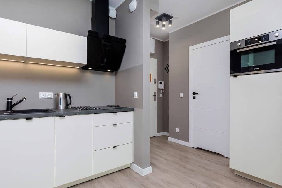 A modern kitchen equipped with sleek appliances, white cabinets, and ample countertop space.elektryczna, kuchenka mikrofalowa