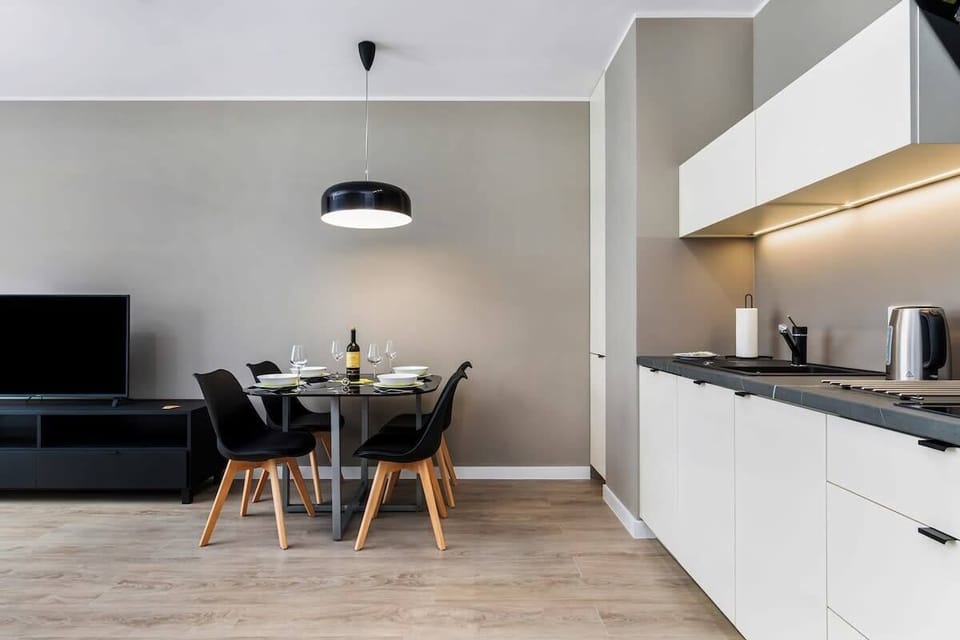 A dining area with a round black table, black chairs, and elegant tableware.