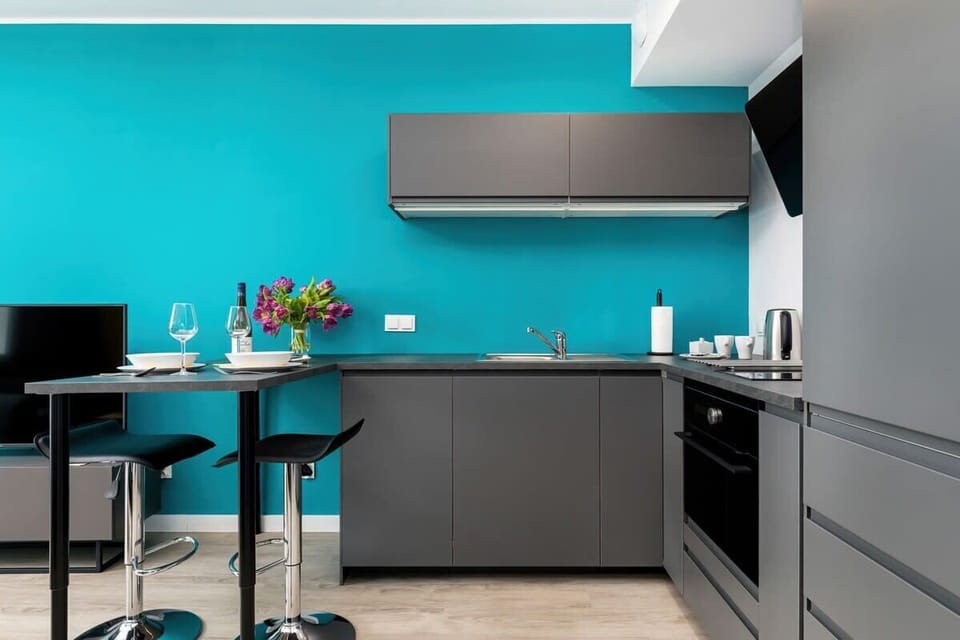 A modern kitchen with a black-and-gray color scheme. Bar stools are set along a counter for casual dining.