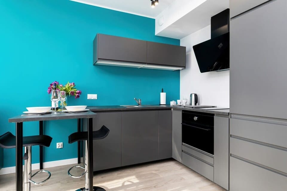 A modern kitchen with a black-and-gray color scheme. Bar stools are set along a counter for casual dining.