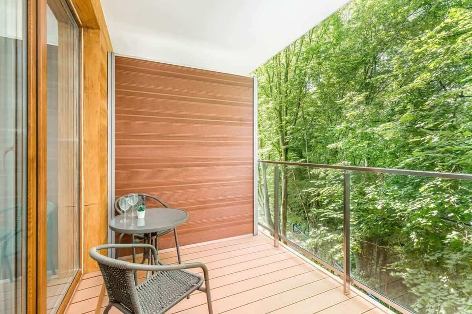 A close-up view of a balcony with a wooden floor and railing, offering a relaxing space surrounded by nature.