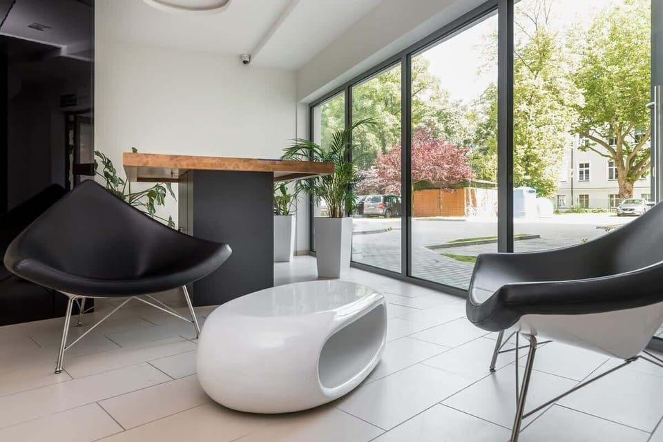 A seating area with modern furniture, including a pair of sleek black chairs and white round tables.