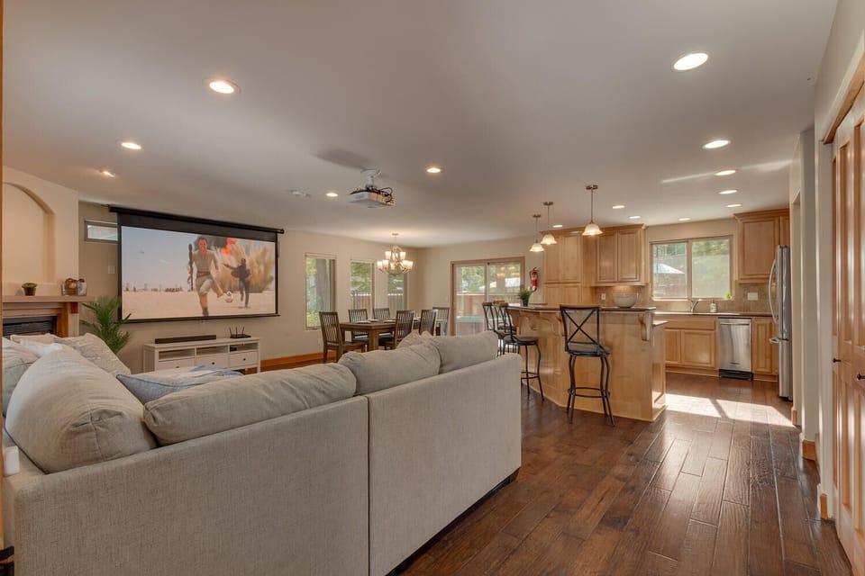 - Large open living area with kitchen connection  
- Projector screen and rustic wood flooring warmth  
- Ideal for gatherings, cooking, and movie nights
