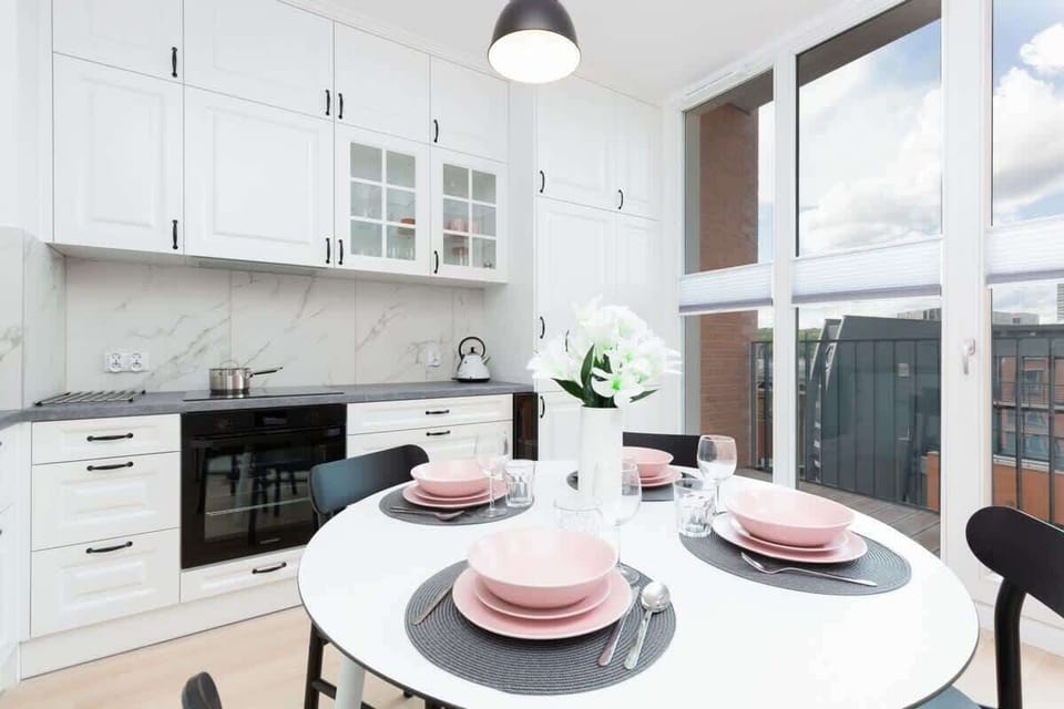 A kitchen corner featuring modern crockery, including pink and black details, set on a dining table for a contemporary touch.