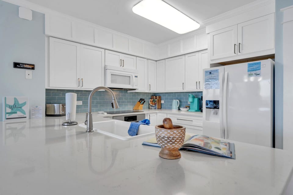 Your bright, fully-equipped kitchen invites you to create memorable meals with gleaming countertops, modern appliances, and coastal charm.