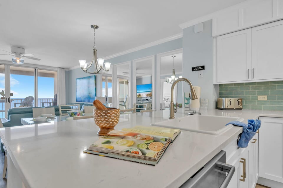 Your modern kitchen features pristine white countertops and stunning gulf views, perfect for preparing meals while enjoying the oceanfront scenery.