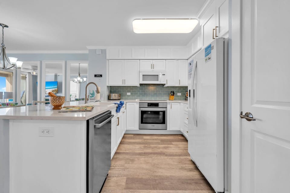Your fully equipped kitchen features pristine white cabinets, stainless steel appliances, and elegant quartz countertops perfect for preparing meals during your stay.