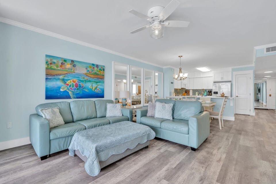 Sink into these plush aqua sofas and feel the coastal breeze from the ceiling fan as you unwind in this bright, airy space.