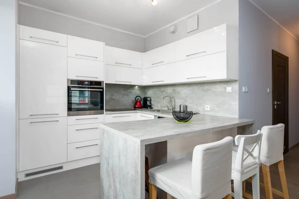A white kitchenette with high-quality finishes, built-in appliances, and a clean, minimalist design.