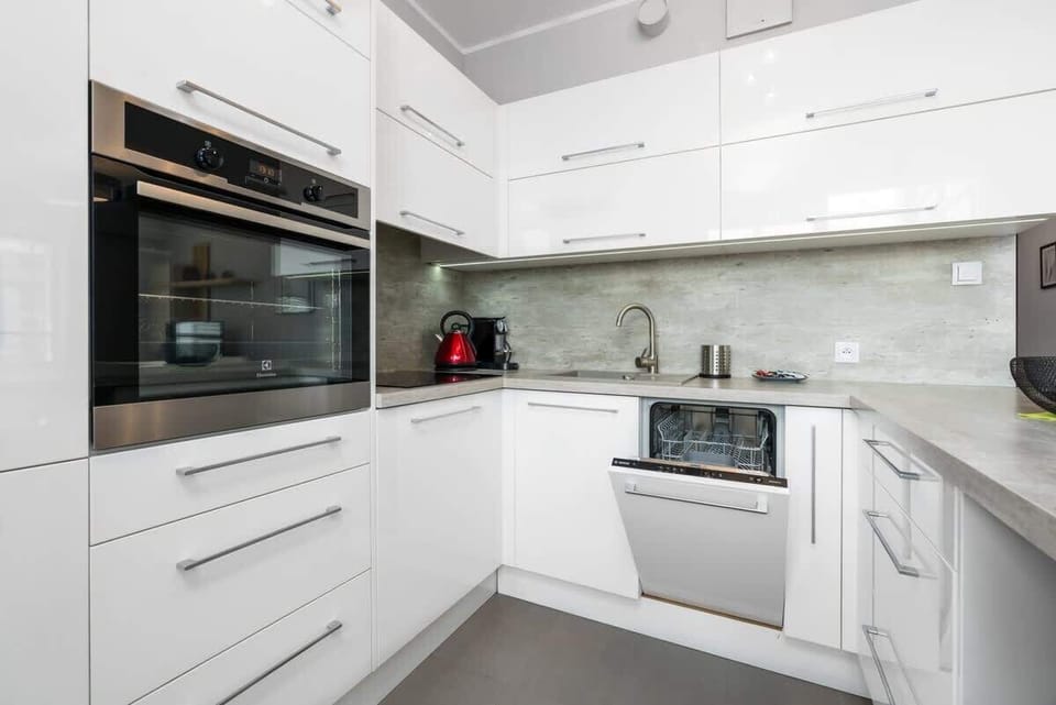 A white kitchenette with high-quality finishes, built-in appliances, and a clean, minimalist design.