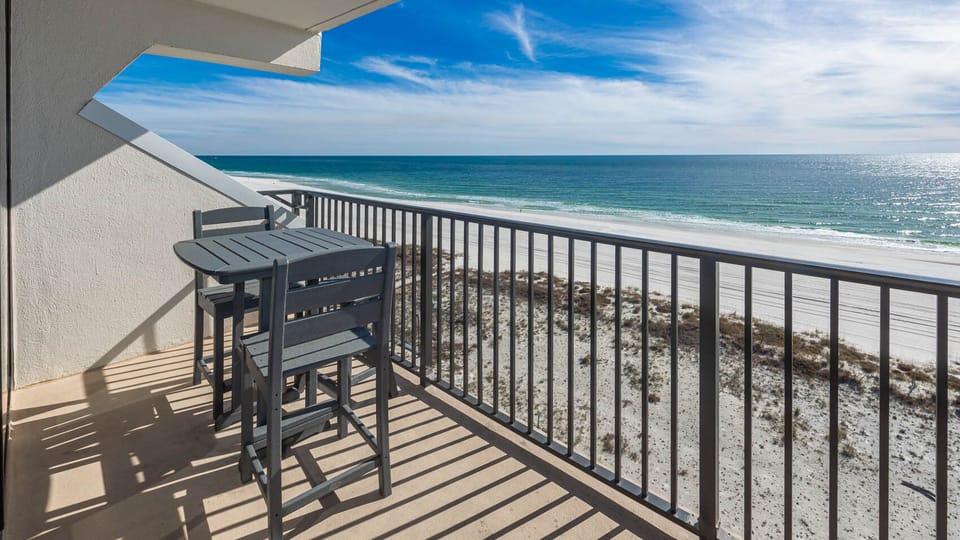 Enjoy a scenic beachfront view from this balcony with stylish outdoor seating, perfect for relaxation