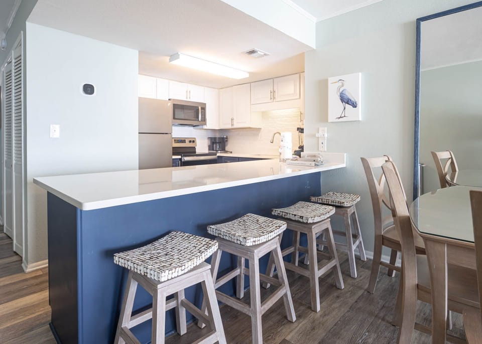This kitchen features sleek stainless appliances, granite countertops, and a stylish breakfast bar with woven stools