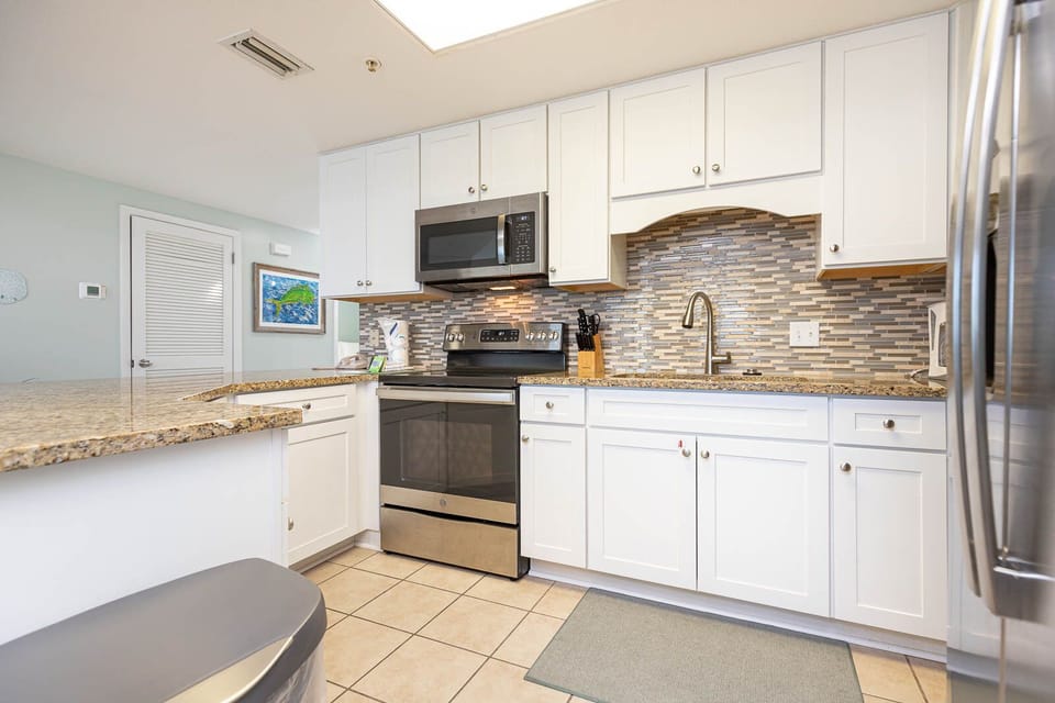 Prepare meals in the sleek kitchen featuring granite countertops, stainless appliances, and stylish tile accents