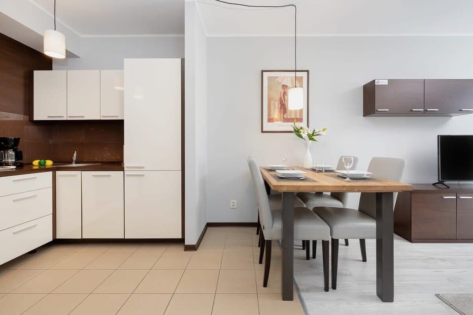 Kitchenette with dining area, toaster, stove, cupboards, dishwasher, kettle, fridge, and freezer.