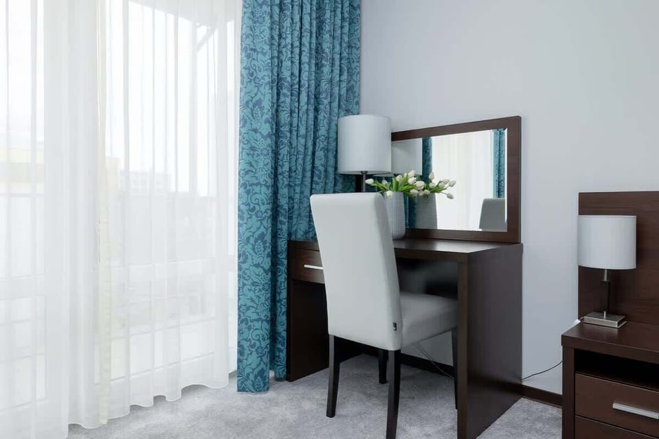 Elegant and stylish bedroom with double bed, nightstand, desk, chair, night lamp, mirror and wardrobe.