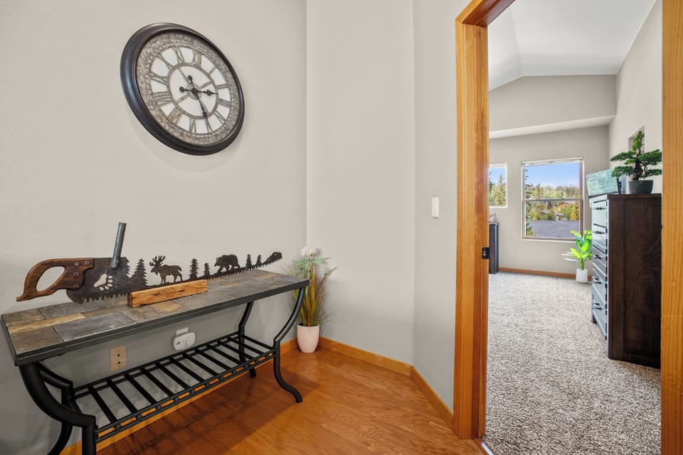 Charming hallway entry featuring a rustic decorative clock and accent table with bench seating. Offers a warm welcome and practical space for everyday use.