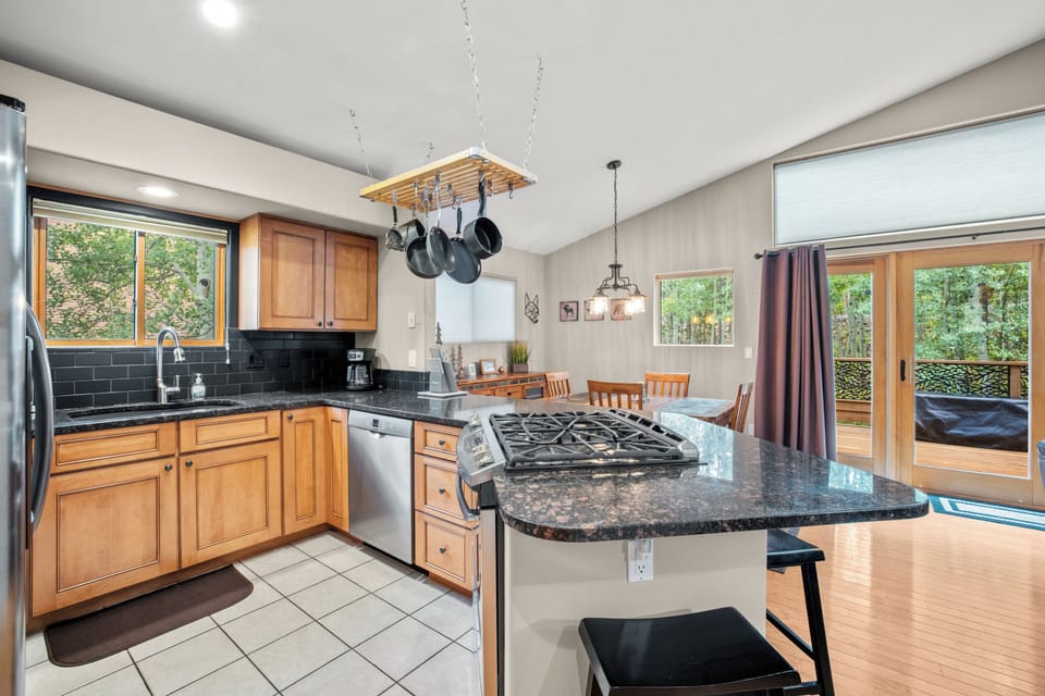 Modern full kitchen with stainless steel appliances and warm wood cabinetry, complemented by a spacious breakfast bar—ideal for casual dining or entertaining after a day on the mountain.