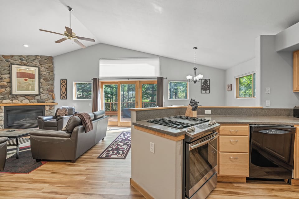 Bright, airy great room with vaulted ceilings, a cozy stone fireplace, and seamless flow from the kitchen’s gas range to the spacious living and dining areas. Large windows and sliding doors open to a private deck surrounded by Aspens, perfect for entertai