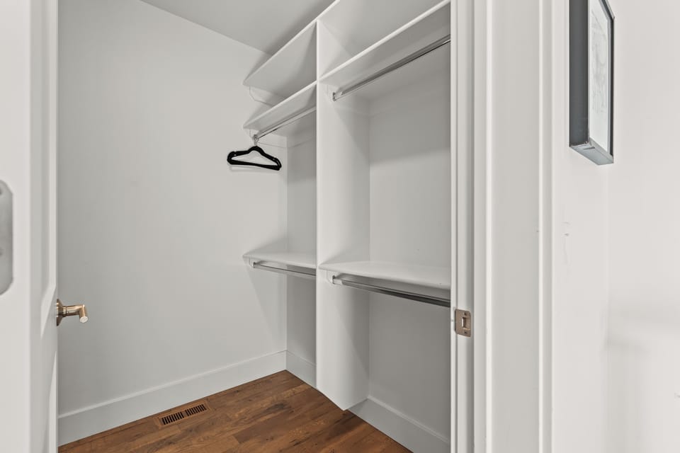 Your spacious walk-in closet offers organized storage with dual hanging rods and shelving.