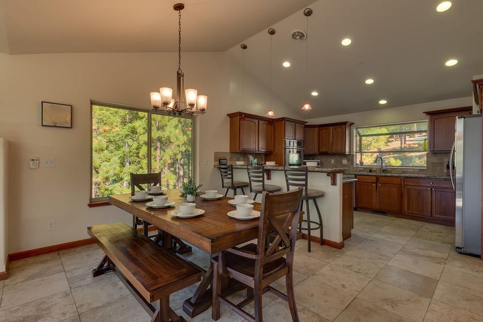 - Dining area with wooden farmhouse table and chairs  
- Kitchen with bar seating and stainless appliances  
- Spacious cabin layout with forest window views