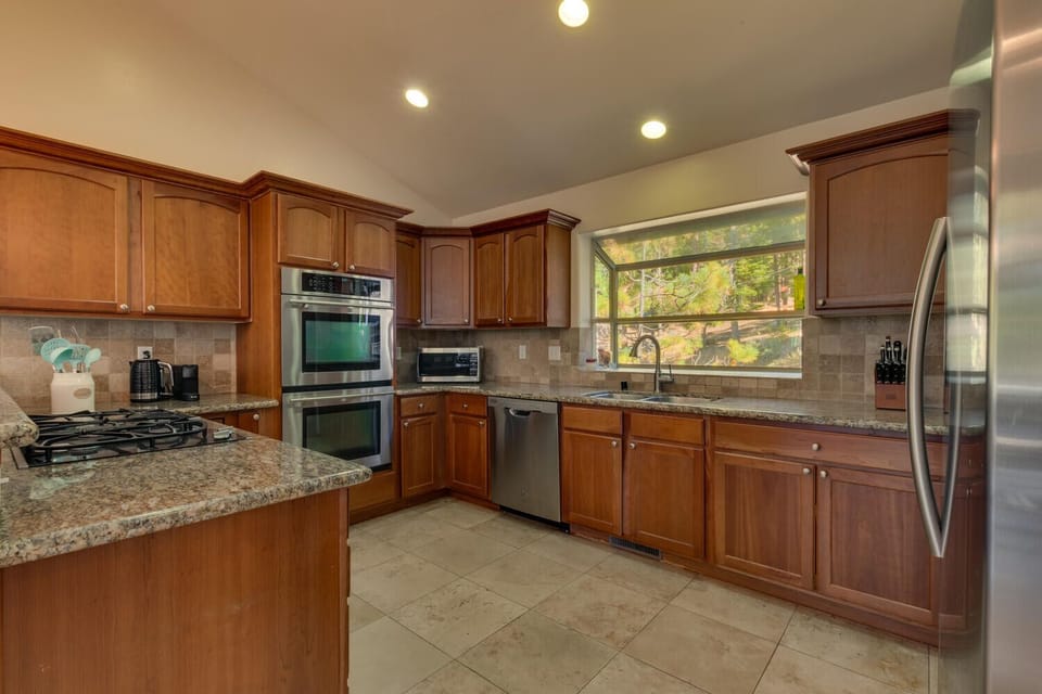 - Fully equipped kitchen with double ovens and stove  
- Granite counters with large window and forest view  
- Stainless steel appliances for guest convenience