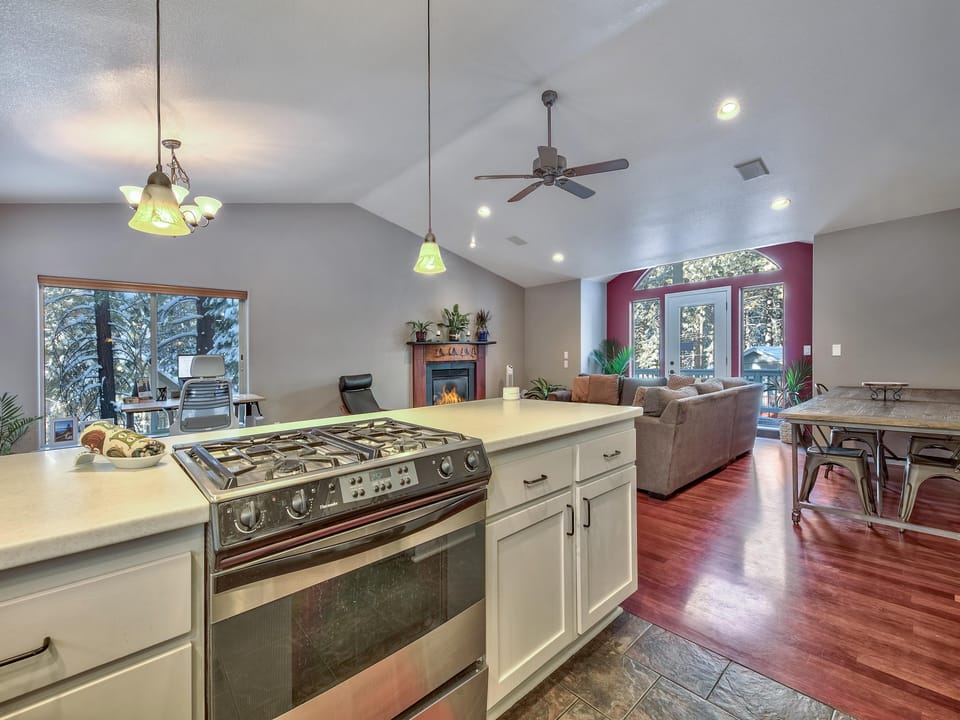 Kitchen island with stainless steel gas stove overlooks living area with gray sectional and red accent wall.
