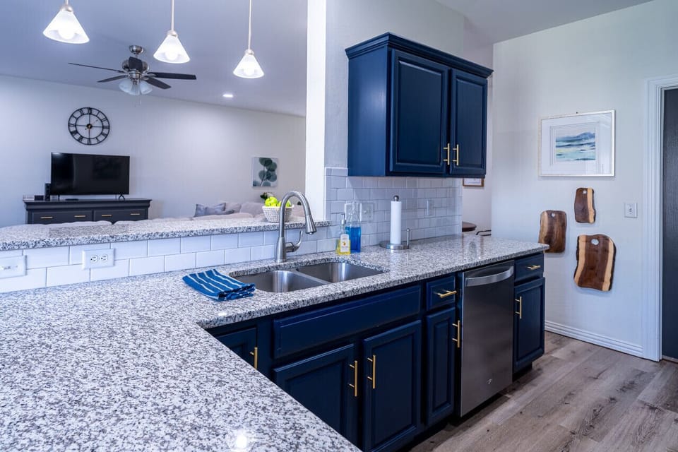 A well-stocked chef`s kitchen featuring stylish navy blue cabinets, granite countertops, and stainless steel appliances.