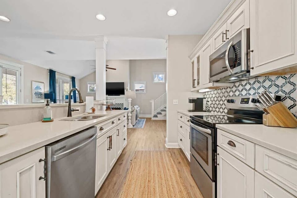 - Prepare meals with ease in a spacious kitchen featuring sleek appliances & a cheerful backsplash - Open layout keeps you connected to the living room while cooking - Bright lighting & clean white cabinetry create a welcoming, coastal inspired vibe