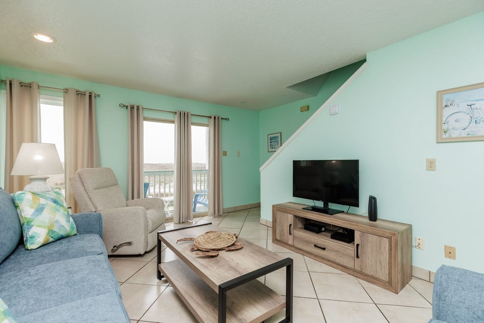 Settle into your coastal-themed living room with comfy seating and entertainment center, perfect for unwinding after beach adventures.