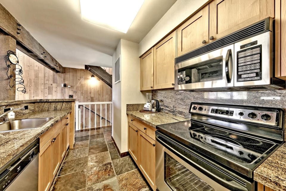 Your fully equipped galley kitchen features granite counters, stainless steel appliances, and warm wood cabinetry for home-style meal preparation.