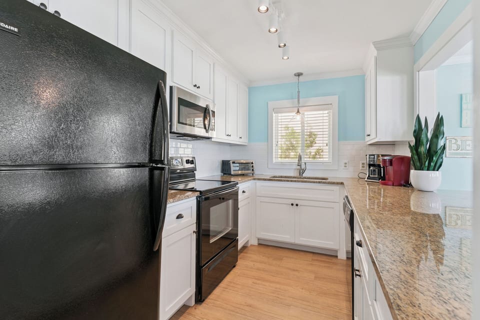 Your bright kitchen features granite countertops, white cabinetry, and modern appliances for home-cooked meals.