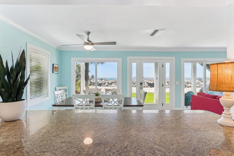 Your bright, open living space flows seamlessly to ocean views through expansive glass doors. Coastal breezes and soft colors invite you to relax at the dining table or unwind on plush seating after sun-filled beach days.
