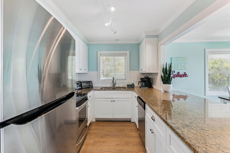 Your fully equipped kitchen features stainless steel appliances, granite countertops, and cheerful coastal decor—perfect for preparing your favorite beach meals in style.