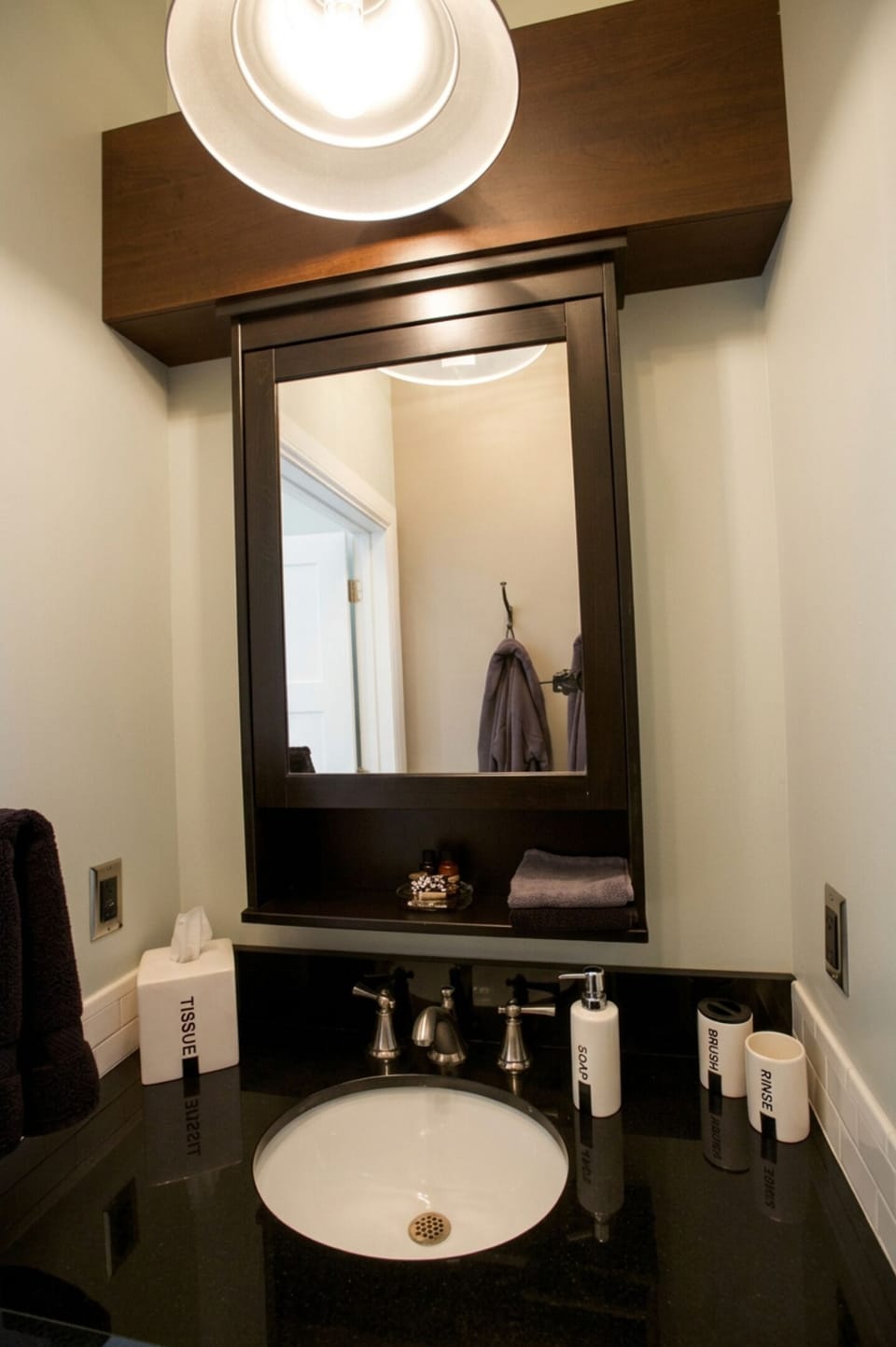 The bathroom mirror is installed on a cabinet holding a few more items for our guests...notice the hooks in the reflection in the mirror