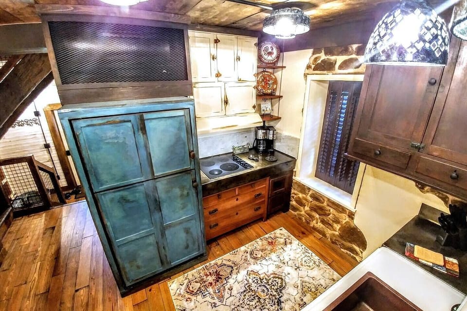 Upper level kitchen features repurposed cabinetry, even a antique pie safe installed upside down on the sandstone walls