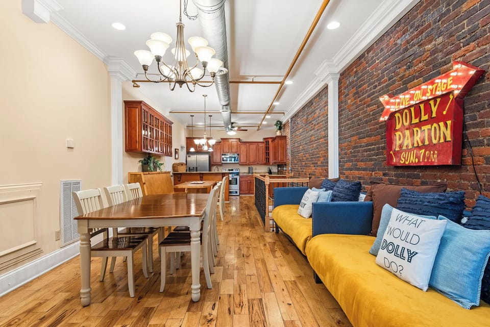 - Open dining area with long table and bright seating for group stays   - Dolly-themed décor adds fun Nashville charm to your Airbnb stay   - Brick walls and warm lighting create a memorable gathering spot
