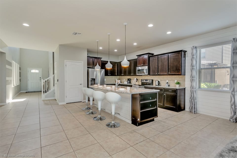 View 2 of modern style kitchen including microwave, stove, double door refrigerator and barstool sea