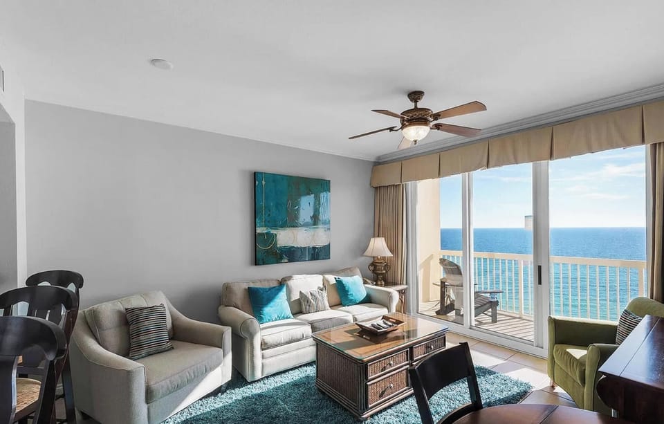 Relax in your bright living space with stunning ocean views through floor-to-ceiling windows and comfortable seating perfect for unwinding.