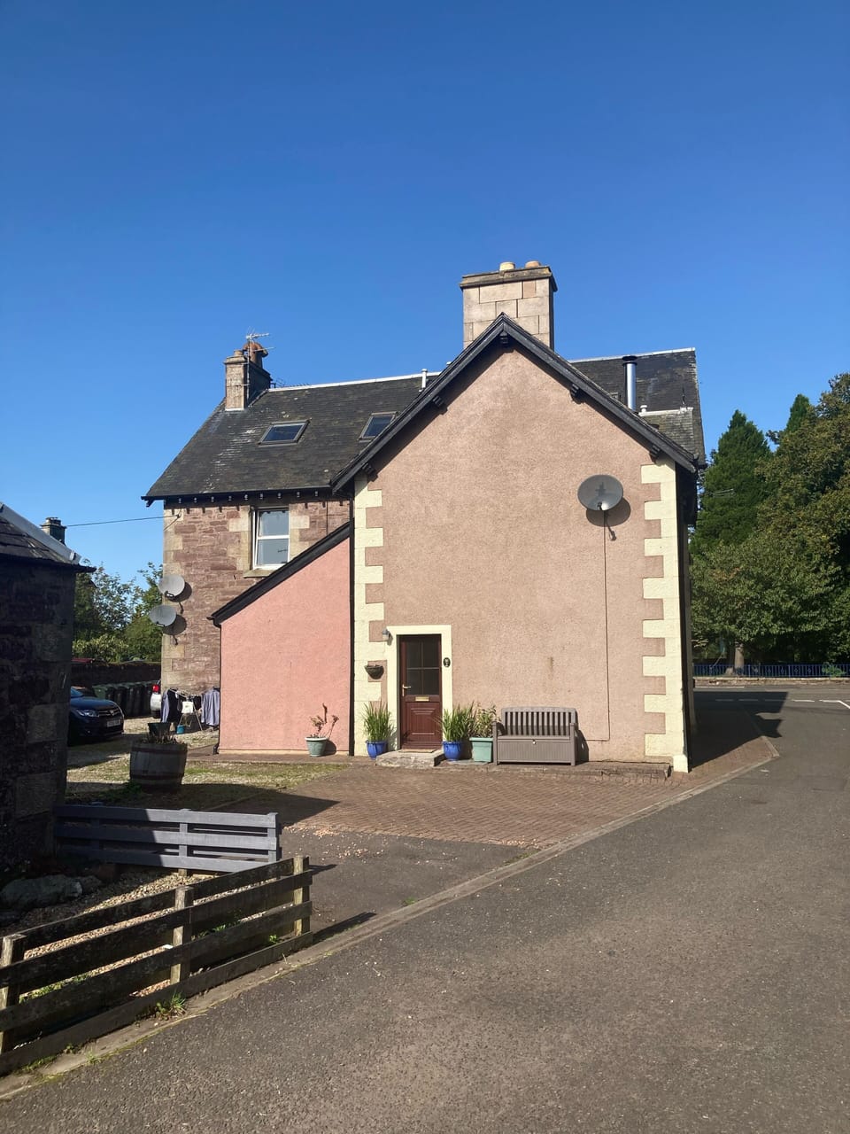 Side view of the house with garden bench seating area. 