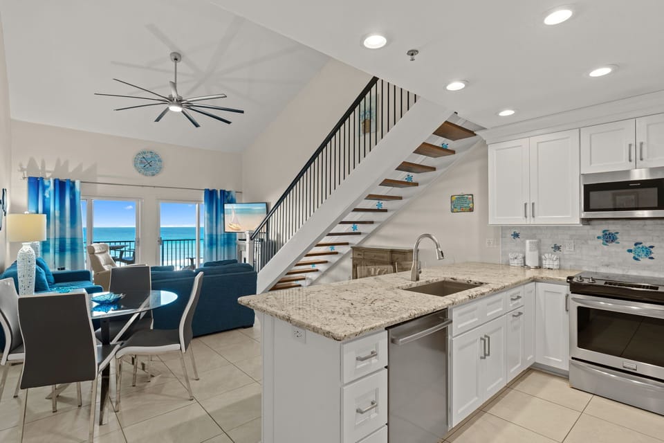 Unwind in your bright, open-concept living space where the modern kitchen flows into a cozy lounge area, all framed by stunning ocean views you'll enjoy every day.