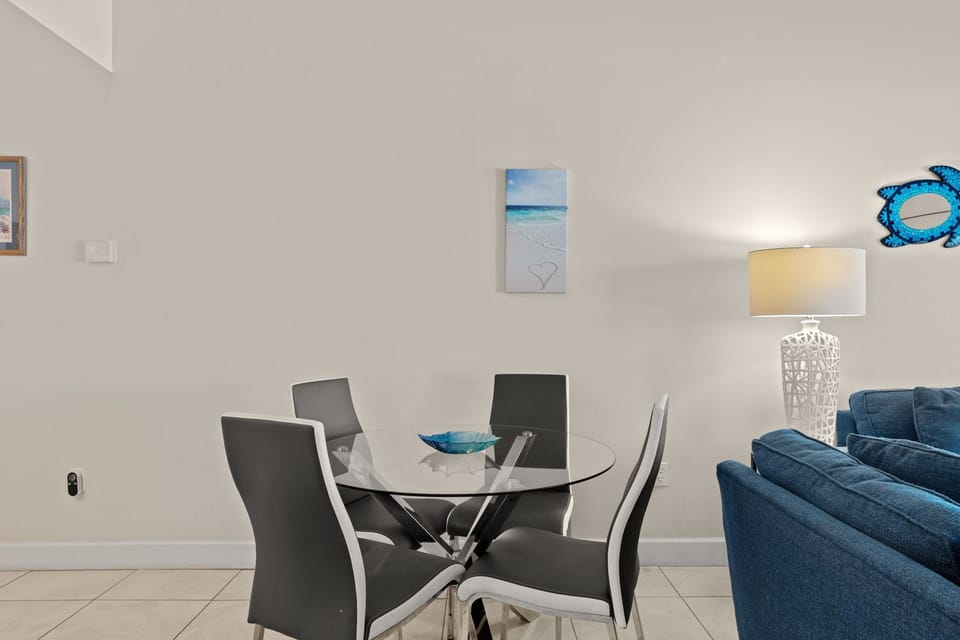 Gather around this sleek glass dining table, where modern style meets coastal charm. The soft lighting and ocean-inspired décor create a welcoming atmosphere for your meals together.