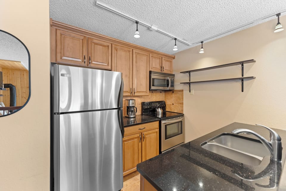 Your fully equipped kitchen features granite counters, stainless appliances, and warm wood cabinets for comfortable home cooking.