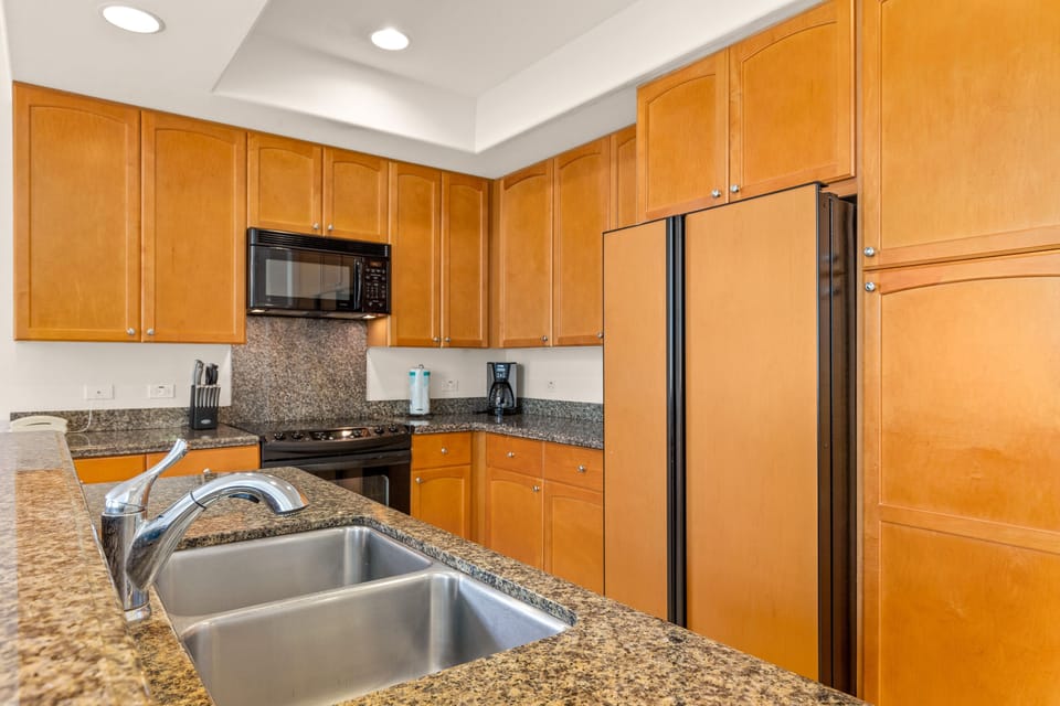 Your fully equipped kitchen features warm wood cabinetry, granite countertops, and modern stainless appliances, including a microwave, stove, and full-sized refrigerator—everything you need to prepare home-cooked meals during your stay.