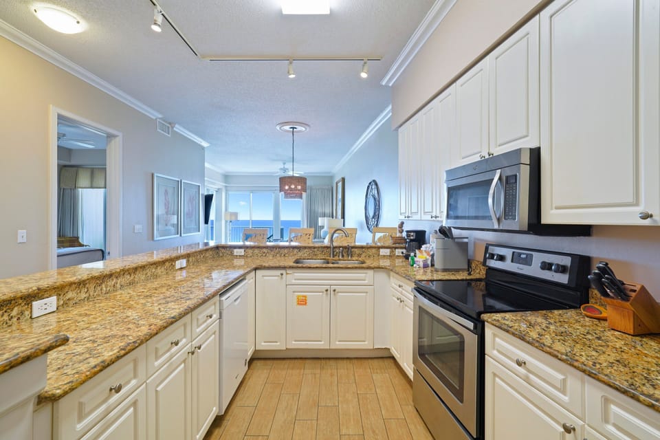 Bright beachfront condo kitchen leading to balcony and Gulf views
