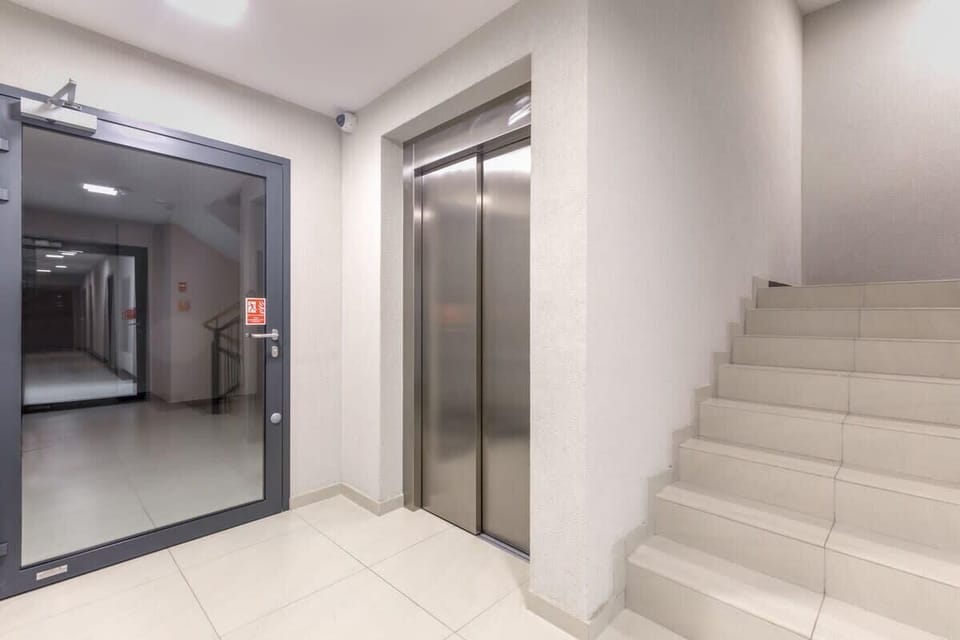 A well-lit staircase in an apartment building, featuring light walls and modern, minimalistic architecture.