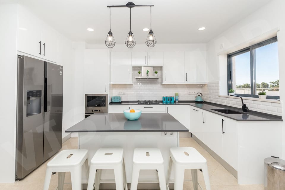 Modern fully equipped kitchen in Apartment Vista Mar, Lagos, featuring sleek dark countertops, stainless steel appliances, stylish pendant lighting, and a breakfast bar with seating, perfect for self-catering holidays in the Algarve