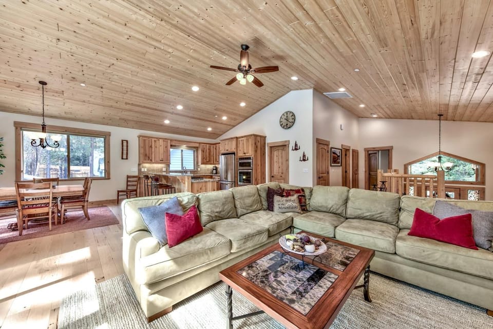 Relax in your spacious living room featuring soaring wood ceilings, plush sectional seating, and an open layout connecting to your fully-equipped kitchen.