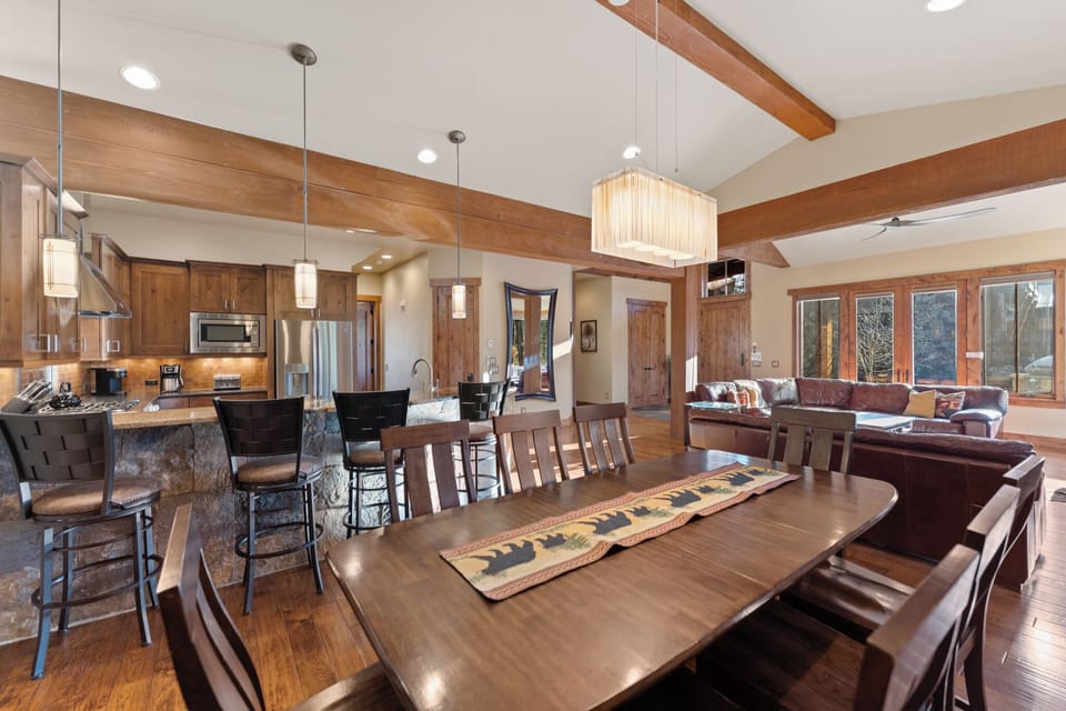 Your open-concept haven flows seamlessly from kitchen to dining to living, with warm wood beams and elegant lighting creating the perfect atmosphere for memorable gatherings.
